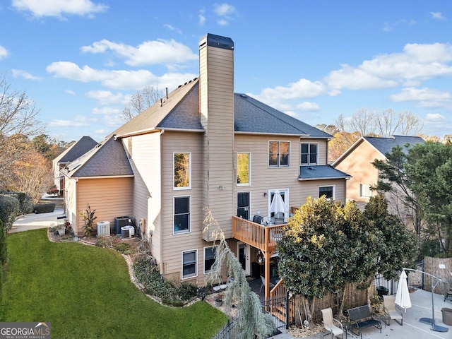 back of house with central AC unit and a yard