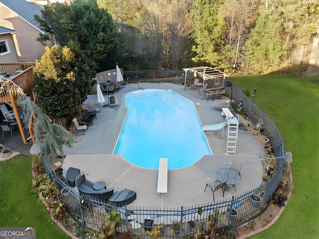 view of pool featuring a diving board, a yard, a water slide, and a patio