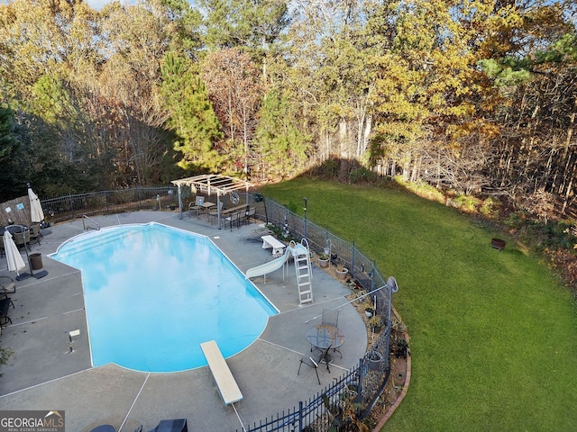 view of swimming pool with a diving board, a patio area, a yard, and a water slide