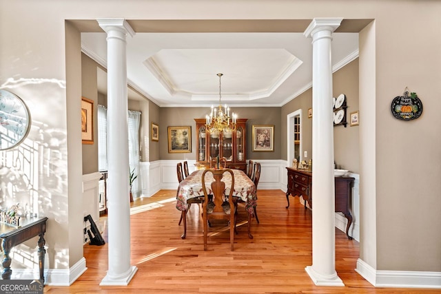 dining space with a raised ceiling, crown molding, light hardwood / wood-style floors, and an inviting chandelier