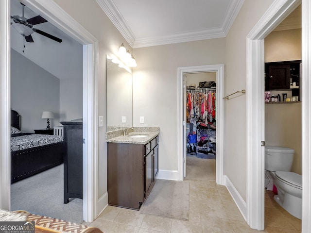 bathroom with toilet, ornamental molding, ceiling fan, vanity, and baseboards