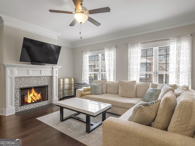 living area with crown molding, ceiling fan, wood finished floors, and a tile fireplace