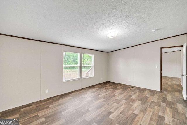 spare room with dark wood-type flooring, a textured ceiling, and ornamental molding