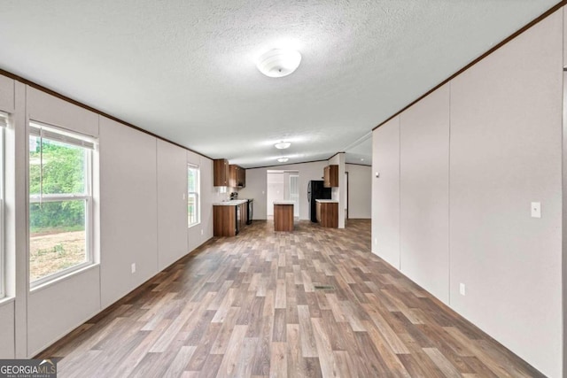 unfurnished living room featuring a textured ceiling, light hardwood / wood-style flooring, and lofted ceiling