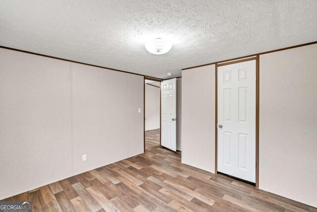 unfurnished bedroom featuring a textured ceiling, light hardwood / wood-style floors, and a closet