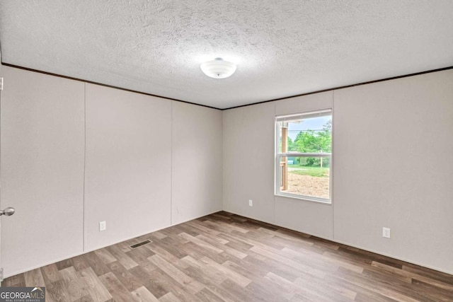 unfurnished room with a textured ceiling and light hardwood / wood-style floors