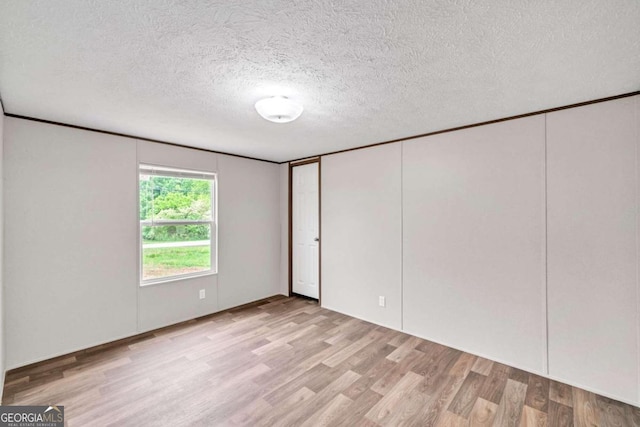 unfurnished room featuring light hardwood / wood-style floors and a textured ceiling