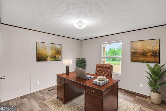 office with a textured ceiling and light wood-type flooring