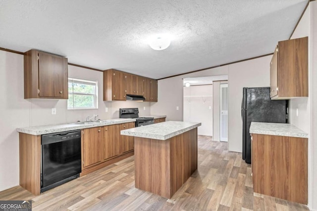 kitchen with a center island, black appliances, light wood-type flooring, a textured ceiling, and ornamental molding