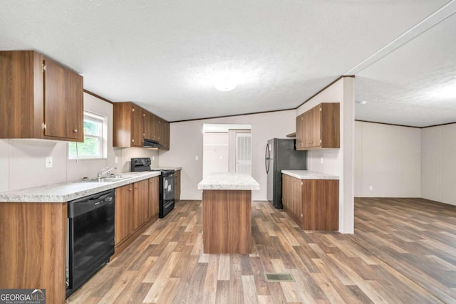 kitchen featuring black appliances, a kitchen island, dark hardwood / wood-style flooring, and a textured ceiling