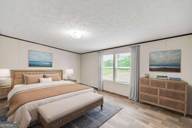 bedroom with ornamental molding, a textured ceiling, and light wood-type flooring