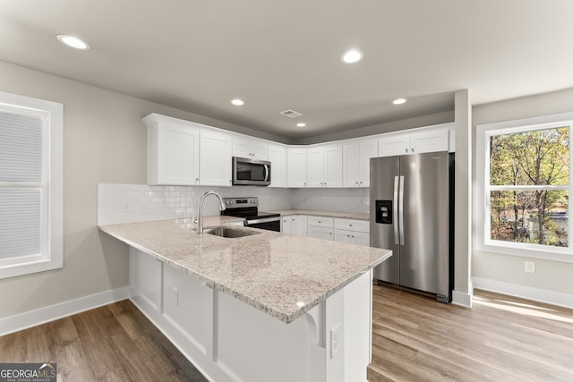 kitchen featuring appliances with stainless steel finishes, light hardwood / wood-style floors, white cabinetry, and sink