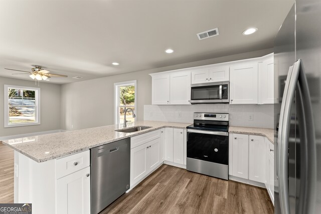 kitchen featuring kitchen peninsula, stainless steel appliances, white cabinets, and sink