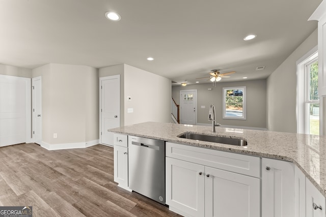 kitchen with white cabinets, sink, stainless steel dishwasher, light stone countertops, and light hardwood / wood-style floors