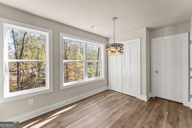 unfurnished dining area with hardwood / wood-style floors and a chandelier