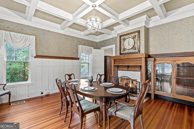 living room featuring hardwood / wood-style floors, a stone fireplace, crown molding, rail lighting, and beam ceiling