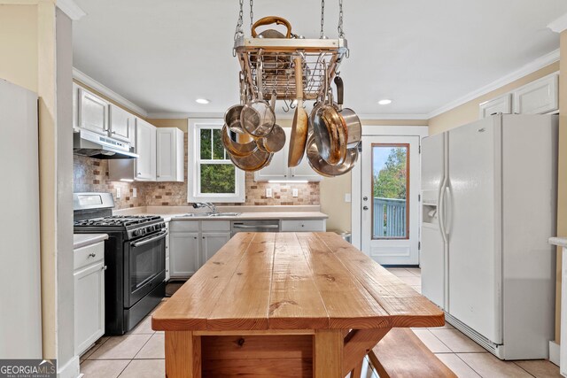 kitchen featuring white cabinets, appliances with stainless steel finishes, crown molding, and light tile patterned flooring