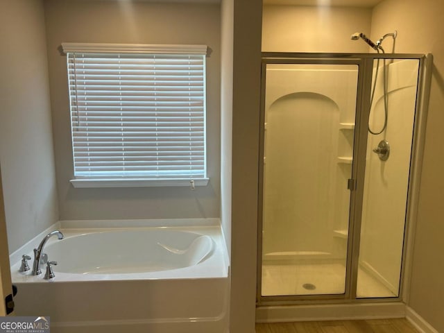 bathroom featuring plus walk in shower and hardwood / wood-style flooring