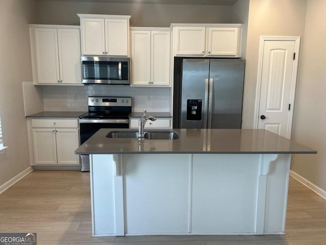 kitchen with sink, stainless steel appliances, tasteful backsplash, an island with sink, and white cabinets