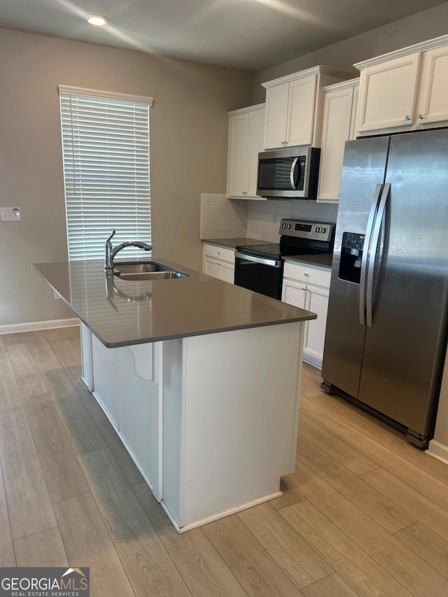 kitchen featuring white cabinetry, sink, light hardwood / wood-style flooring, a kitchen island with sink, and appliances with stainless steel finishes