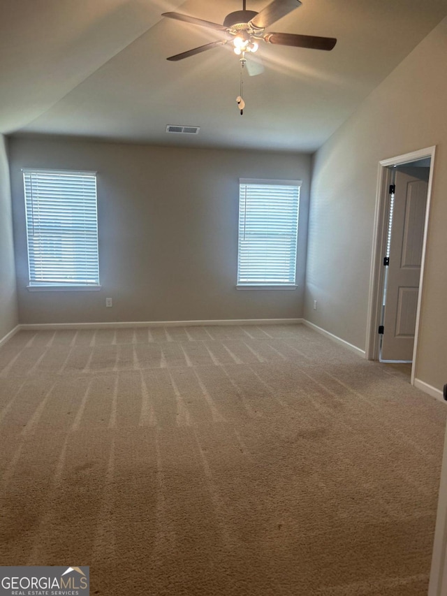 carpeted spare room with ceiling fan and vaulted ceiling