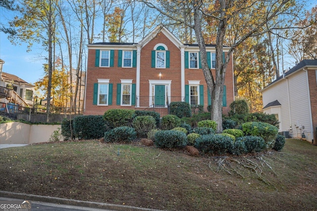 colonial-style house with a front yard and cooling unit