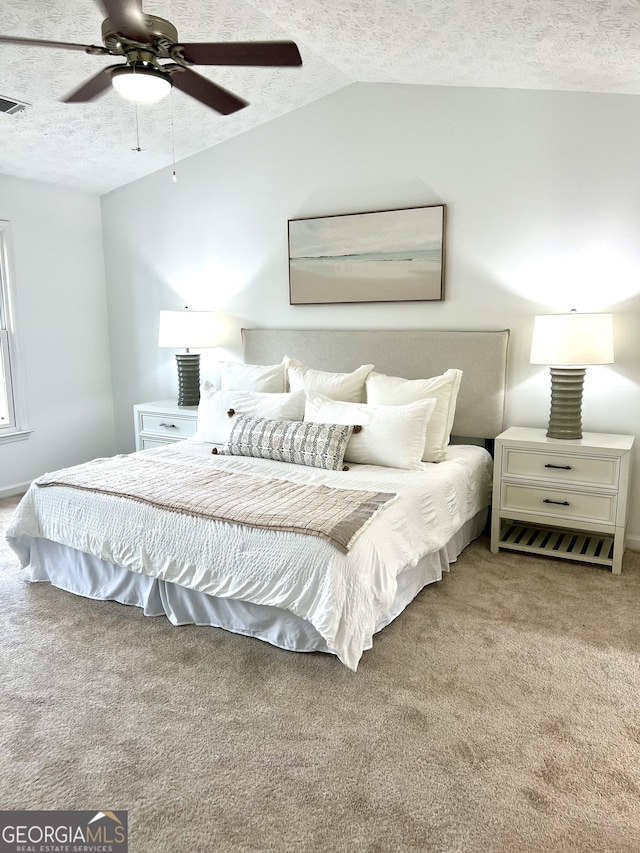 bedroom featuring vaulted ceiling, ceiling fan, carpet floors, and a textured ceiling