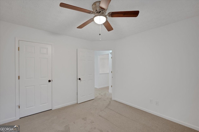 unfurnished bedroom with ceiling fan, light colored carpet, and a textured ceiling