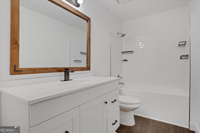 full bathroom with hardwood / wood-style flooring, tiled shower / bath combo, vanity, a textured ceiling, and toilet