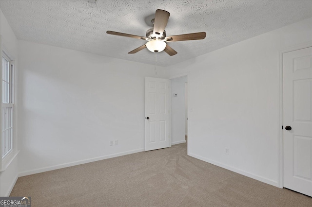 spare room with ceiling fan, light colored carpet, and a textured ceiling