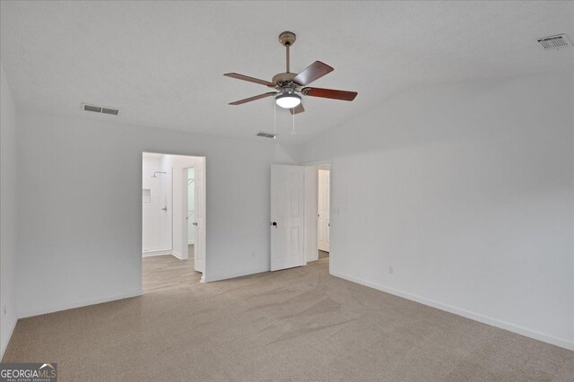 spare room featuring ceiling fan, light colored carpet, vaulted ceiling, and a textured ceiling