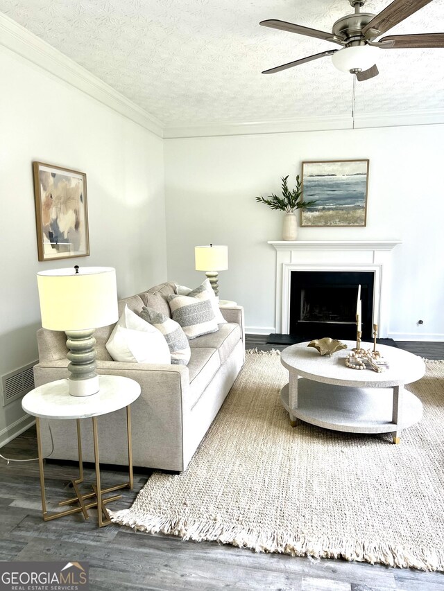 living room with crown molding, ceiling fan, dark hardwood / wood-style floors, and a textured ceiling