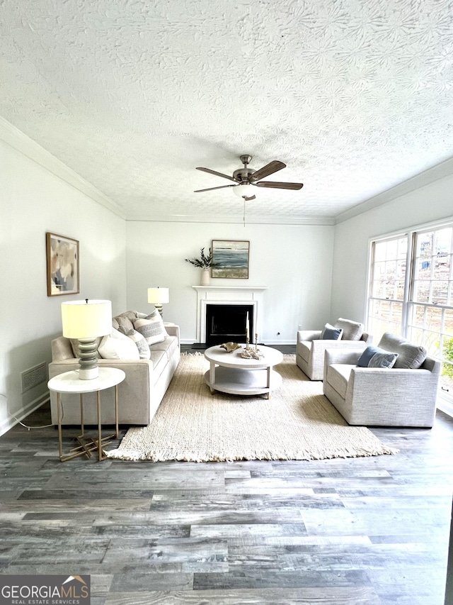 living room with dark wood-type flooring, ceiling fan, crown molding, and a textured ceiling