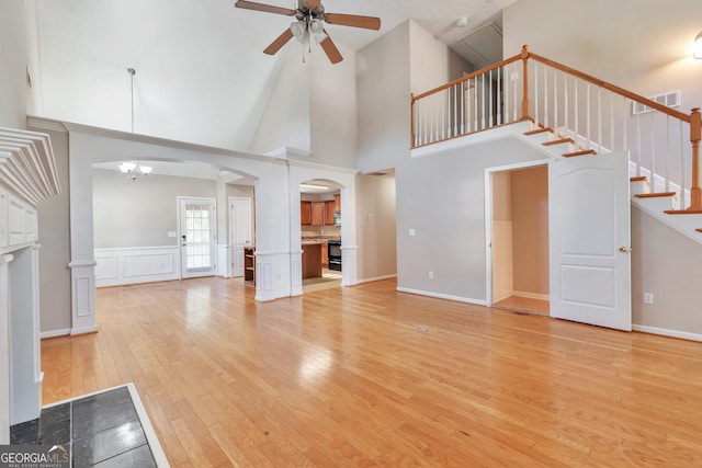 unfurnished living room with hardwood / wood-style floors, high vaulted ceiling, and ceiling fan with notable chandelier