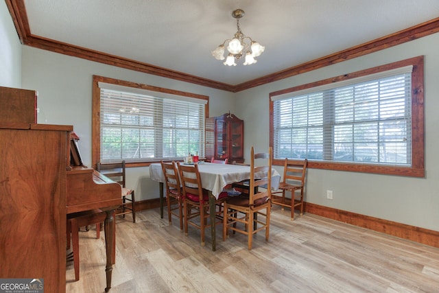 dining space with a notable chandelier, light wood-type flooring, and crown molding