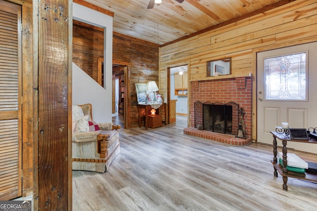 living room featuring hardwood / wood-style floors, wood walls, wooden ceiling, ceiling fan, and a fireplace