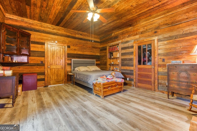 bedroom with ceiling fan, wooden walls, wood ceiling, and light wood-type flooring