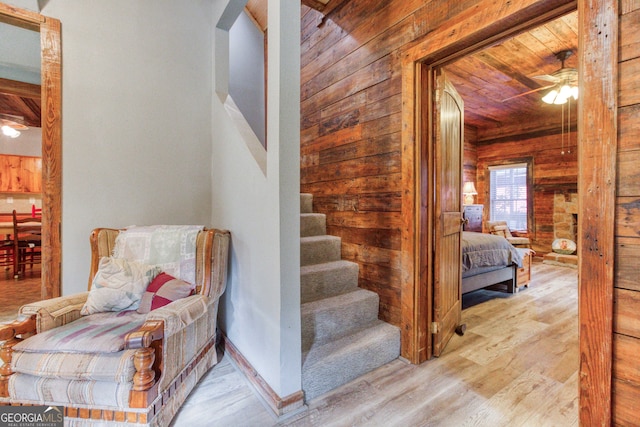 stairway featuring ceiling fan, wooden walls, wood-type flooring, and wooden ceiling