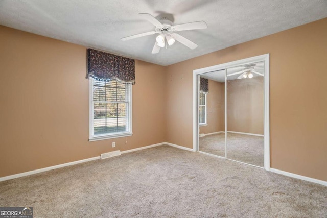 unfurnished bedroom featuring carpet flooring, ceiling fan, a textured ceiling, and a closet