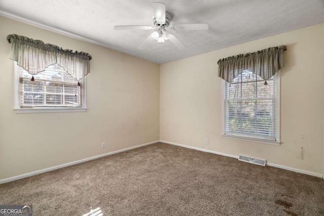 carpeted spare room with ceiling fan and a textured ceiling