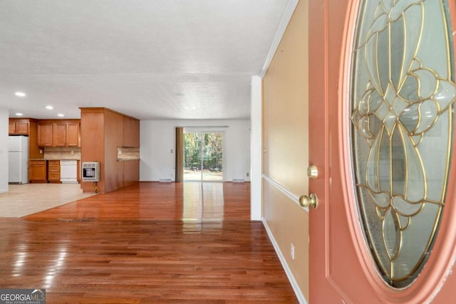 foyer entrance with wood-type flooring, heating unit, and crown molding