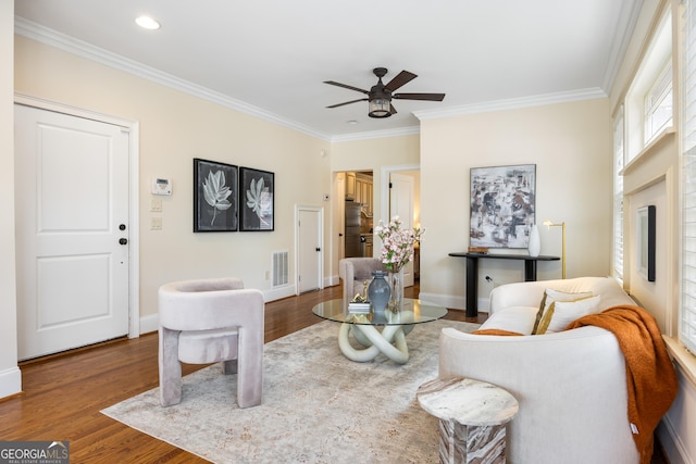 living room with wood-type flooring, ceiling fan, and crown molding