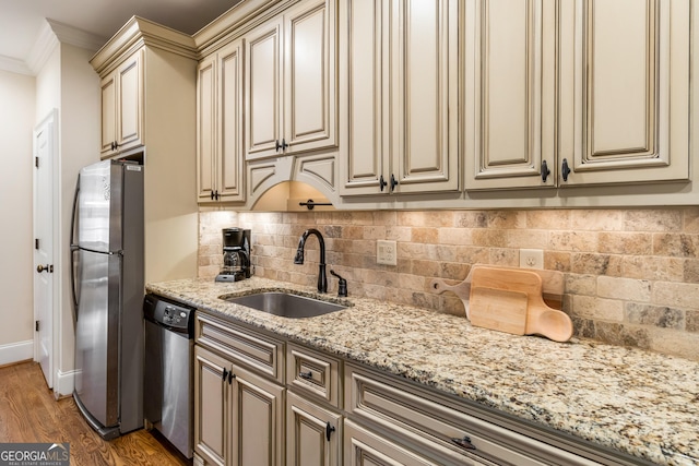 kitchen featuring appliances with stainless steel finishes, sink, light stone counters, crown molding, and cream cabinets