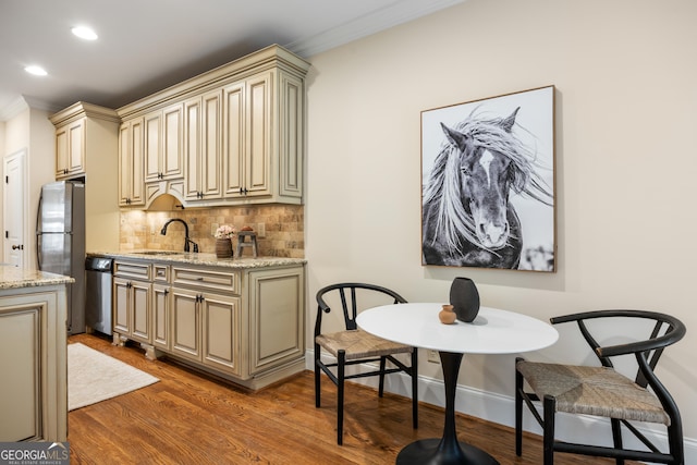 kitchen with sink, tasteful backsplash, dark hardwood / wood-style flooring, light stone countertops, and cream cabinetry