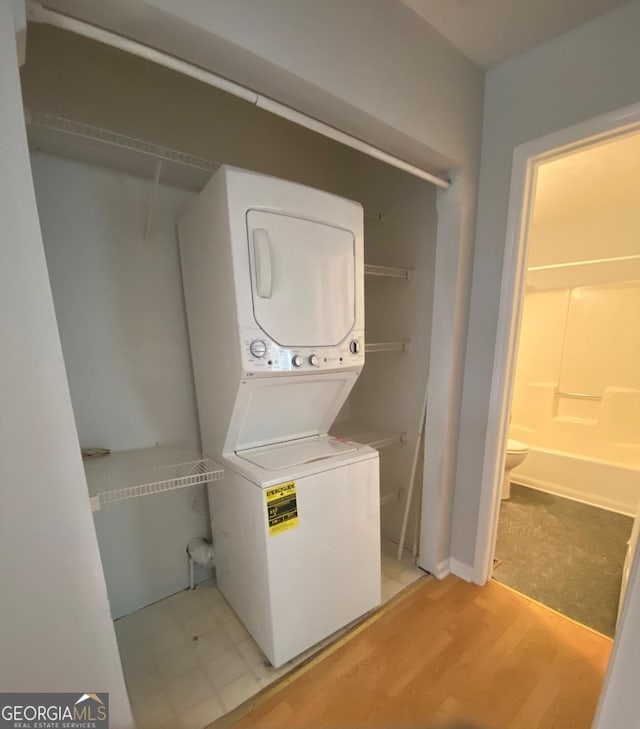 clothes washing area with stacked washer and dryer and light wood-type flooring