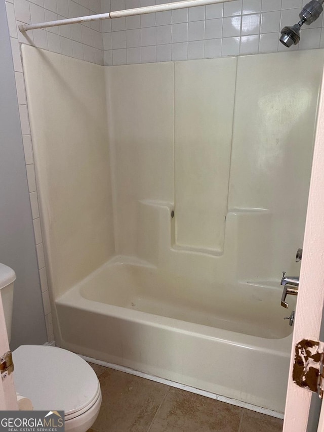 bathroom featuring tile patterned flooring, bathing tub / shower combination, and toilet