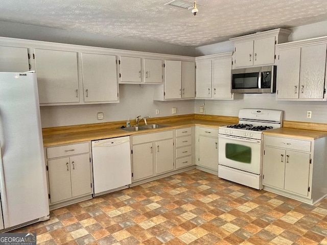 kitchen with a textured ceiling, white appliances, white cabinetry, and sink