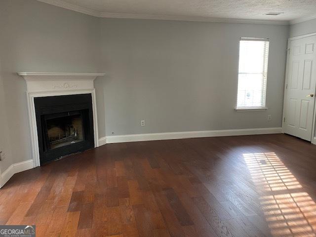 unfurnished living room featuring a textured ceiling, dark hardwood / wood-style floors, and crown molding