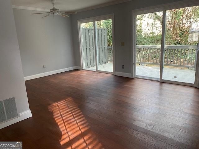 empty room with dark hardwood / wood-style flooring, ceiling fan, plenty of natural light, and crown molding