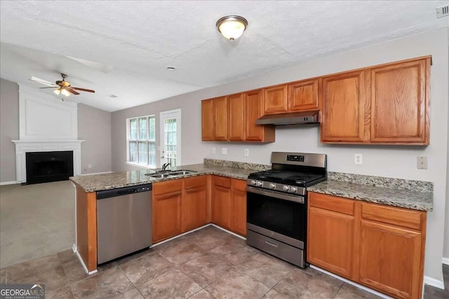 kitchen featuring a fireplace, appliances with stainless steel finishes, a textured ceiling, and sink